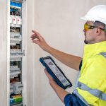 Man, an electrical technician working in a switchboard with fuses. Installation and connection of electrical equipment.